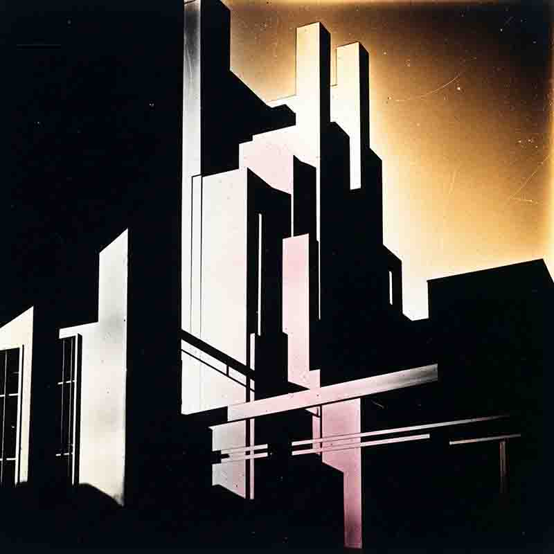 Abstrakte und hochkontrastreiche Farbfotografie, die eine stilisierte, konstruktivistisch anmutende städtische Silhouette oder ein Modell von Hochhäusern darstellt. Vertikale und horizontale geometrische Formen ragen aus der Dunkelheit empor und werden durch starkes Seitenlicht in leuchtendes Weiß und zarte Rosatöne getaucht.